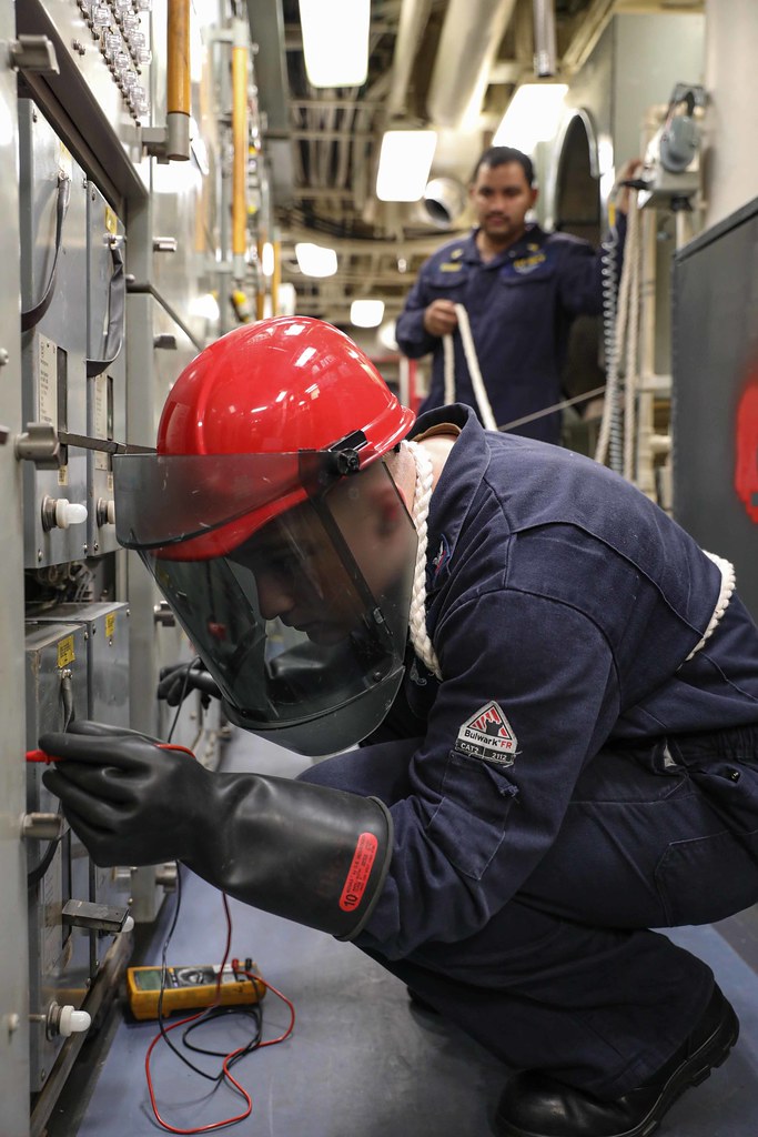 Electrician testing an industrial switchboard panel